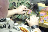 Mario Ingoglia is sewing American flags on 450 Guard uniforms