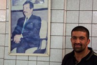 A Tikrit restaurant manager stands next to his prized poster of Saddam Hussein